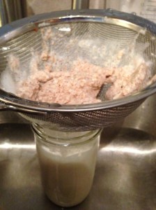 Pouring almond milk through sieve. Residual pulp leftover